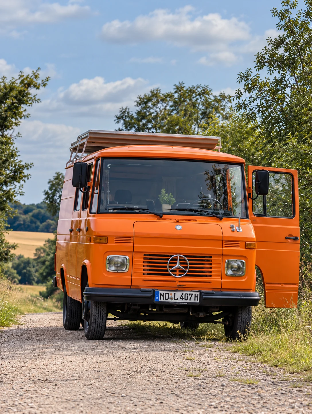 Orangefarbener Mercedes Düdo frontal auf einer Landstraße